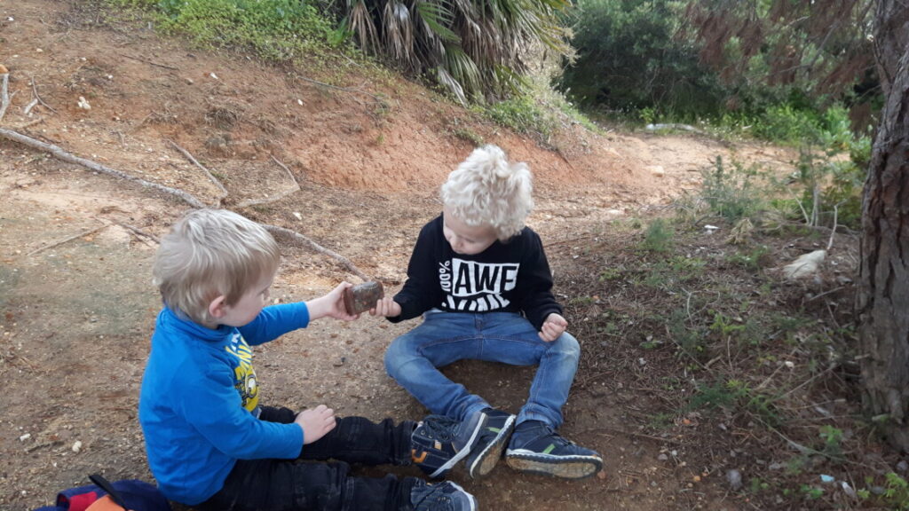 Kinderen met gevonden geocache mini-schatkistje op klif bij Albufeira